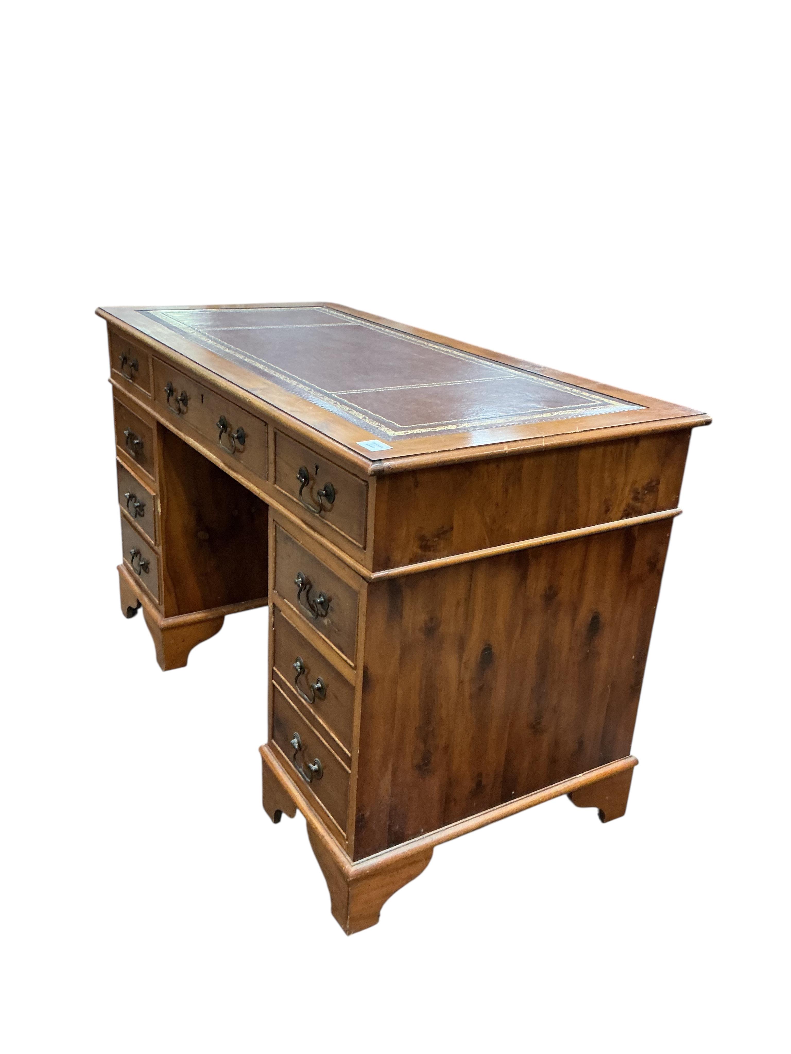 A reproduction yew pedestal desk, width 132cm, depth 61cm, height 77cm and a buttoned burgundy leather swivel desk chair